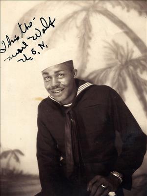 Smiling African American sailor Carl Gipson in uniform during World War II with painting of palm trees in background.